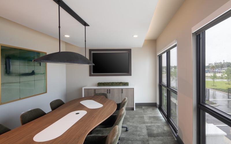room with long table and ample seating with a tv on the wall